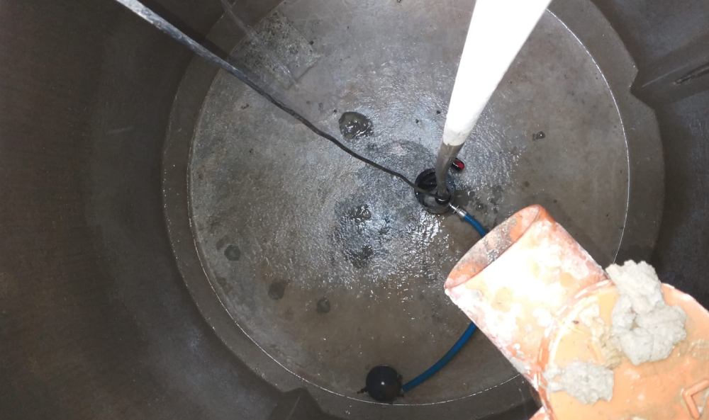 Intérieur d’une cuve ou fosse avec équipements de pompage et câbles immergés, montrant l’état et le fonctionnement du système.